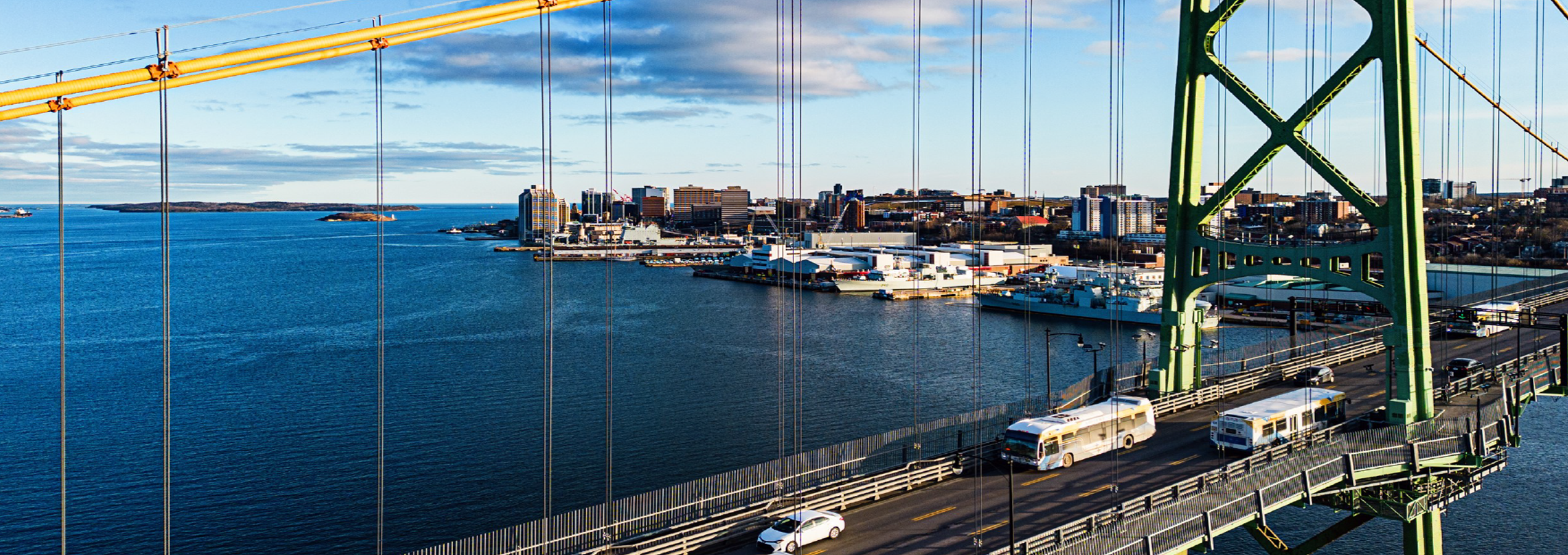 Vue aérienne d’autobus de transport en commun traversant un pont suspendu surplombant un port.