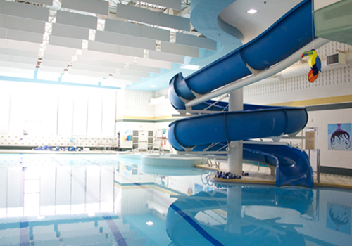 Une piscine intérieure avec un long toboggan aquatique bleu en spirale